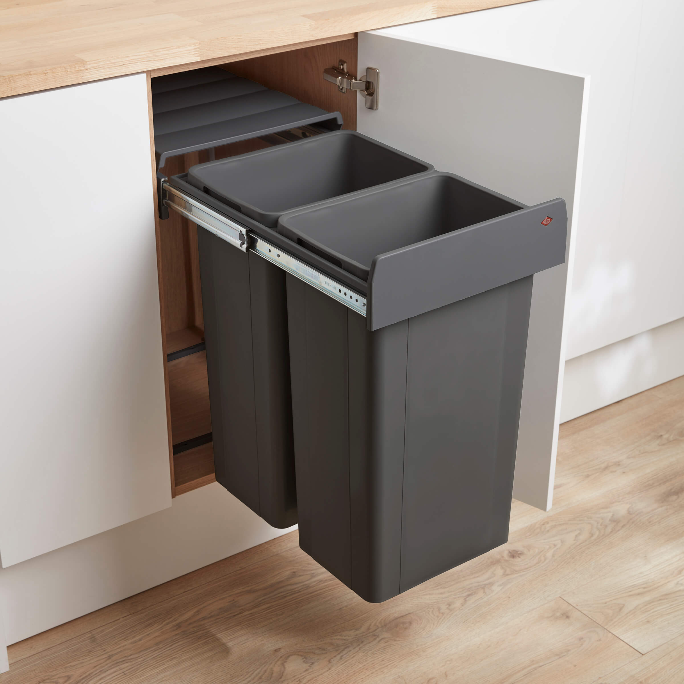 Dark Grey pull-outdual compartment waste bins in a kitchen cabinet with a hinged door.