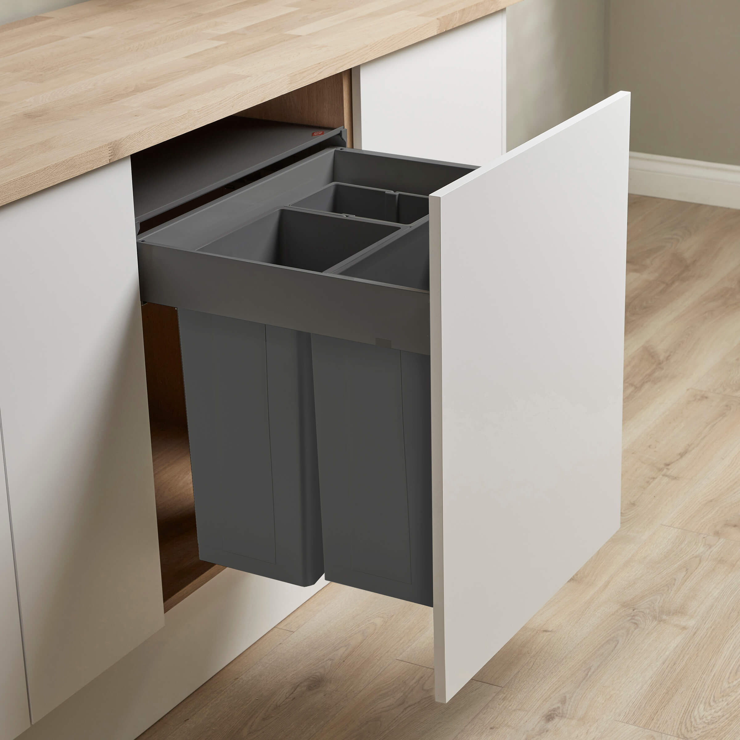 Dark Grey Pullboy Z for Blum Merivobox inside a white cabinet with a wooden floor and wall in the background