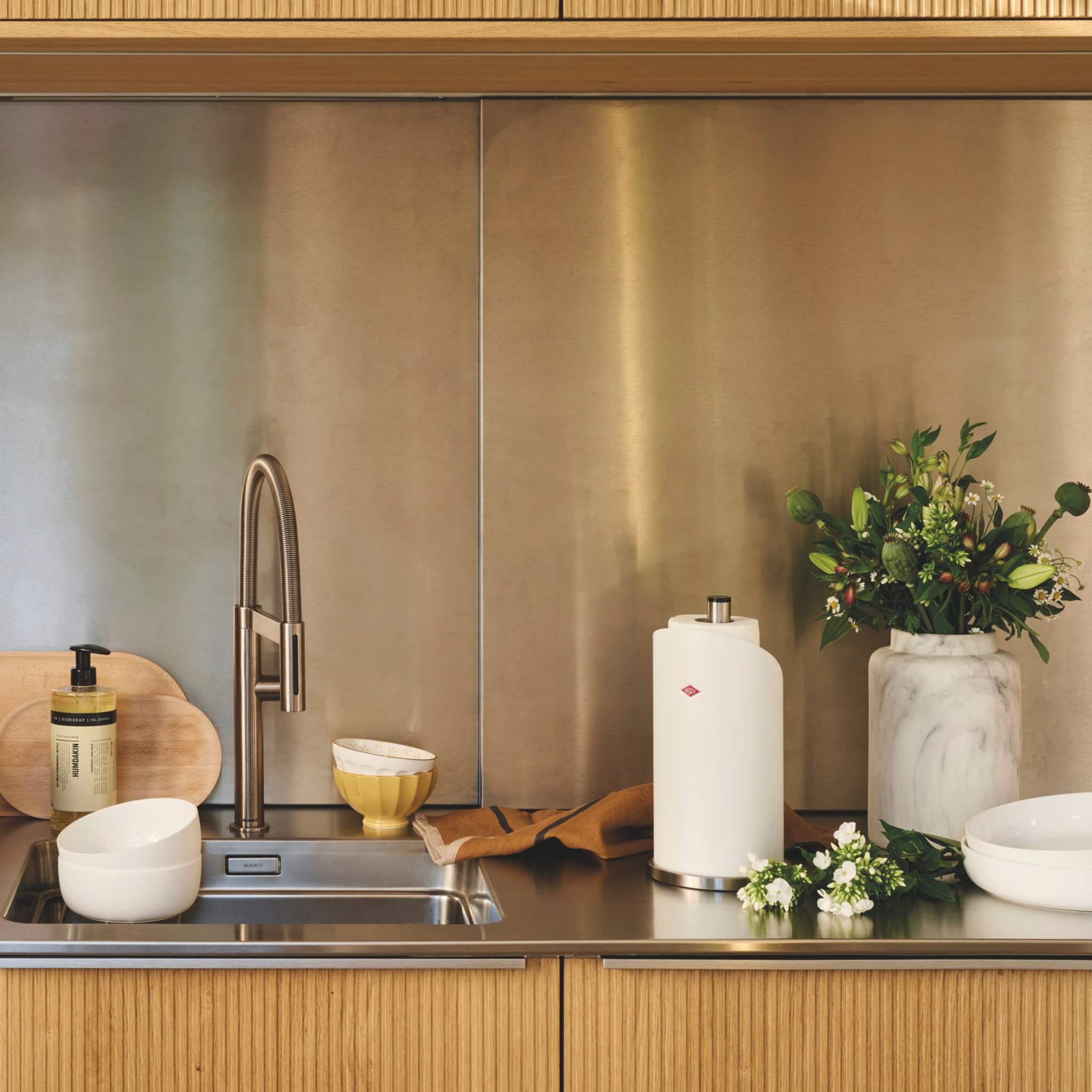Modern kitchen with stainless steel sink, wooden cabinets, and decorative elements Including the wesco paper roll holder in matt sand