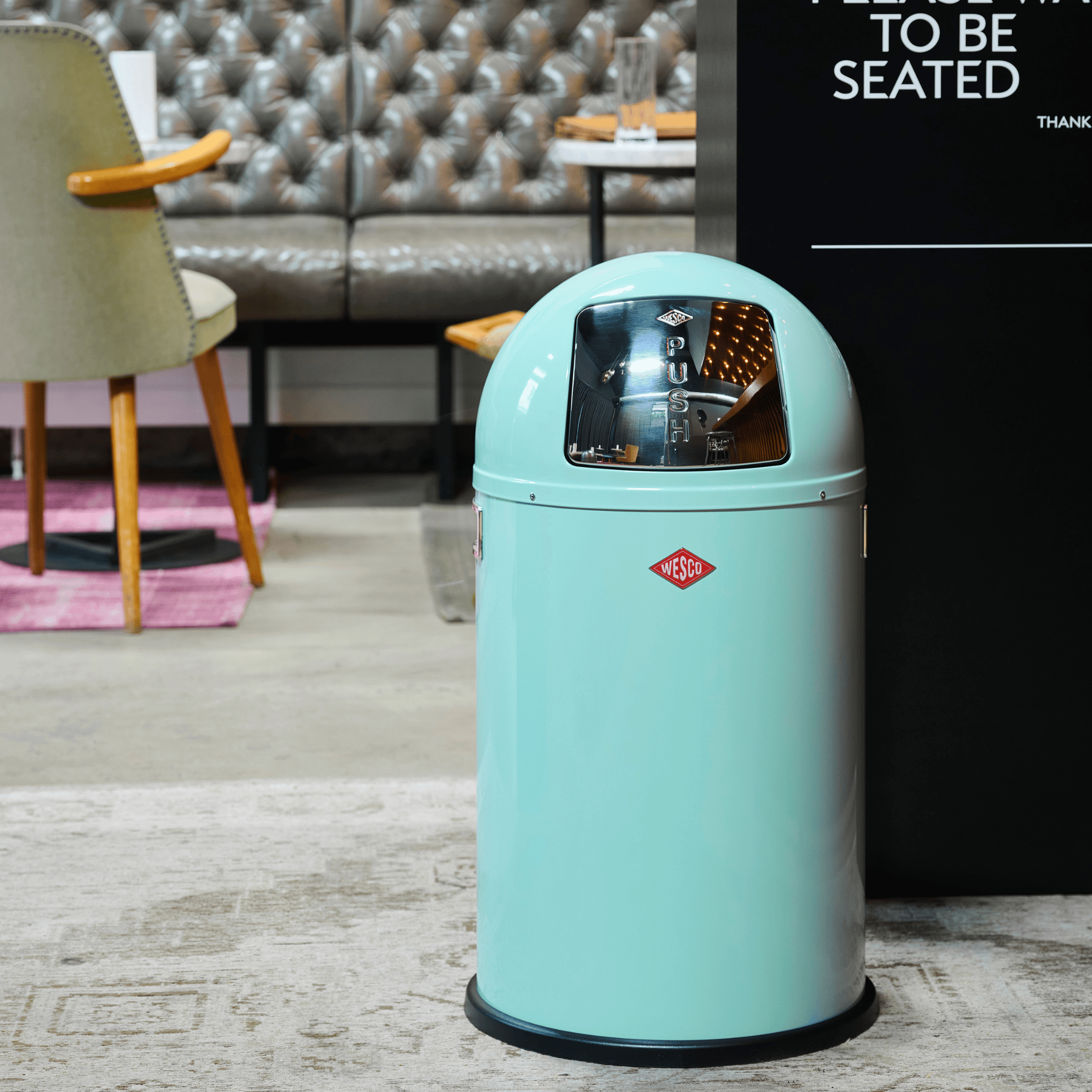 Wesco Pushboy Junior 22l waste bin in Mint in a restaurant setting