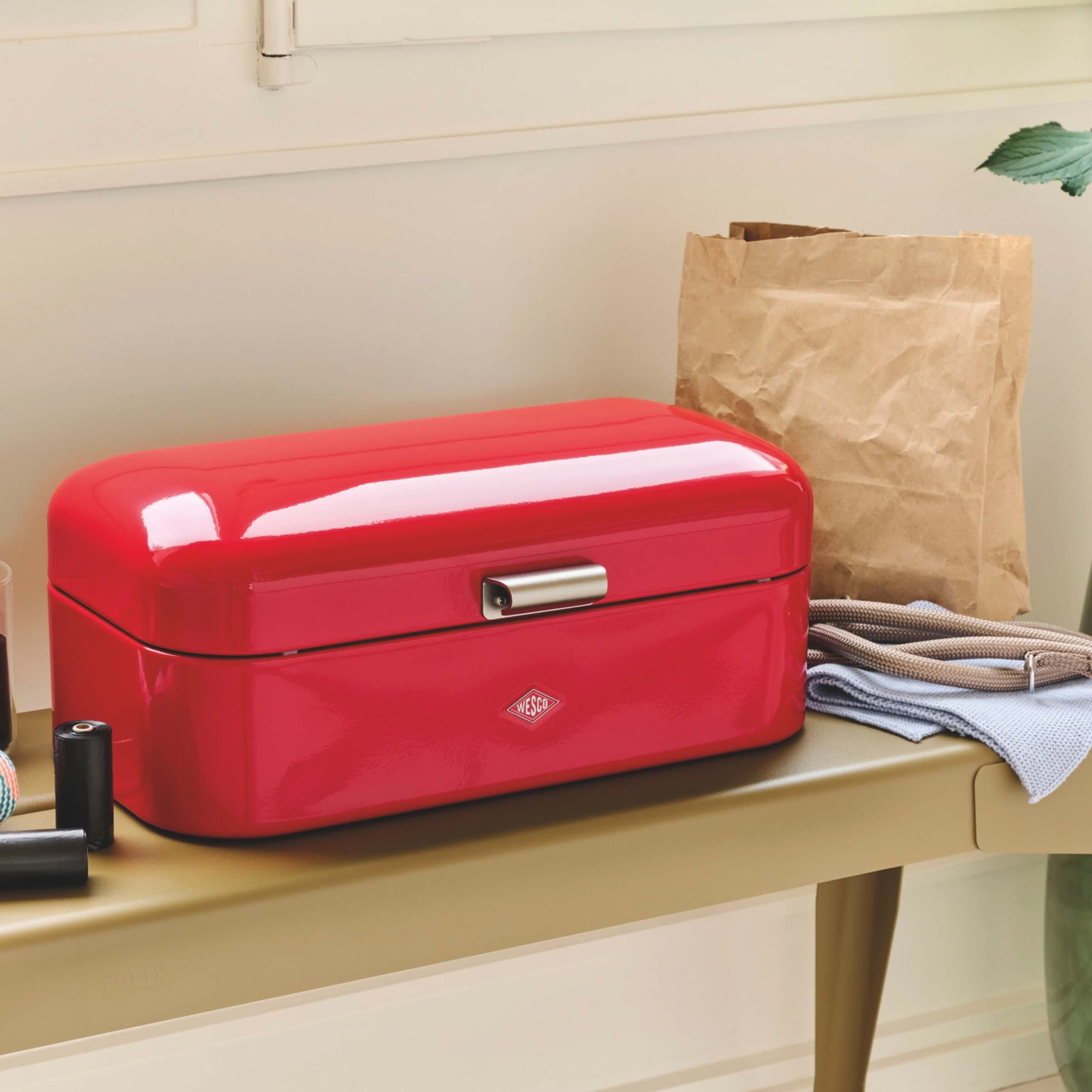 Red bread bin with a brand logo on a wooden surface
