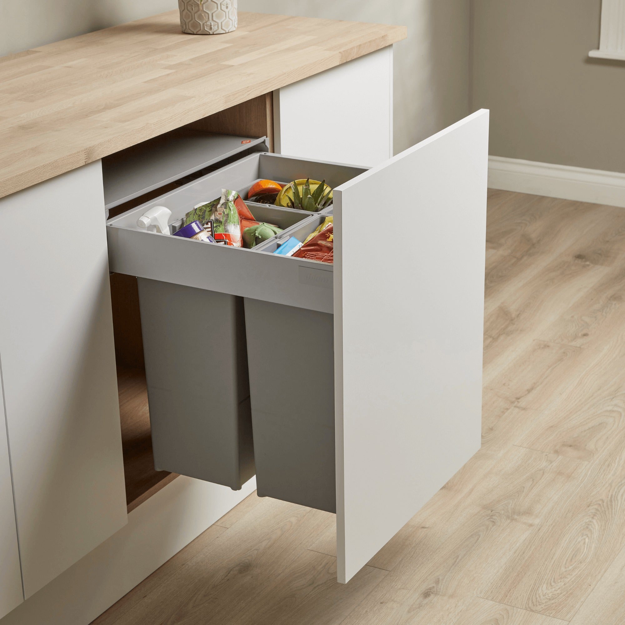 Wesco 600mm four compartment pull-out waste bin system containing recyclable rubbish in a kitchen cabinet.