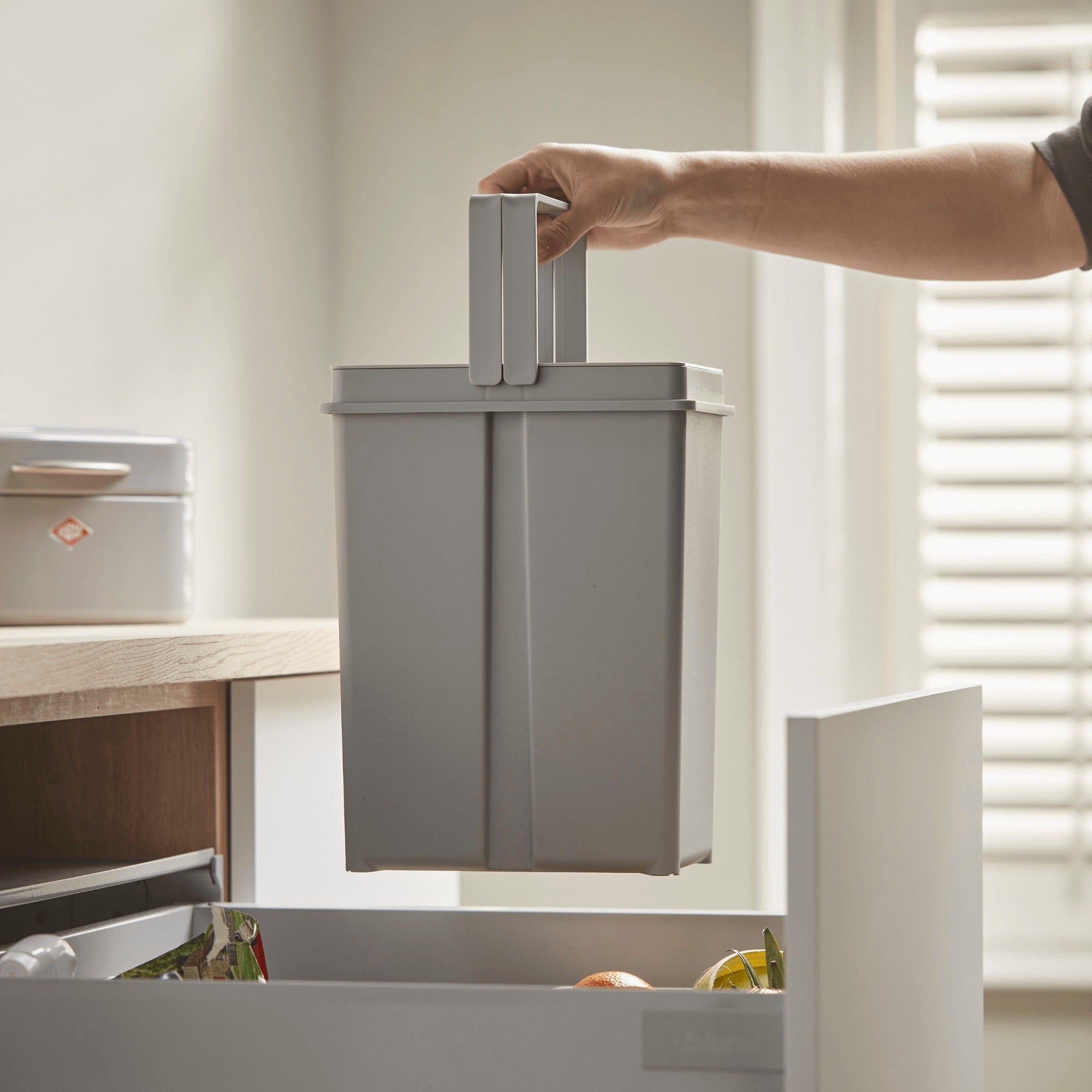 Wesco double plastic handle grey bin being lifted out of the bin system.
