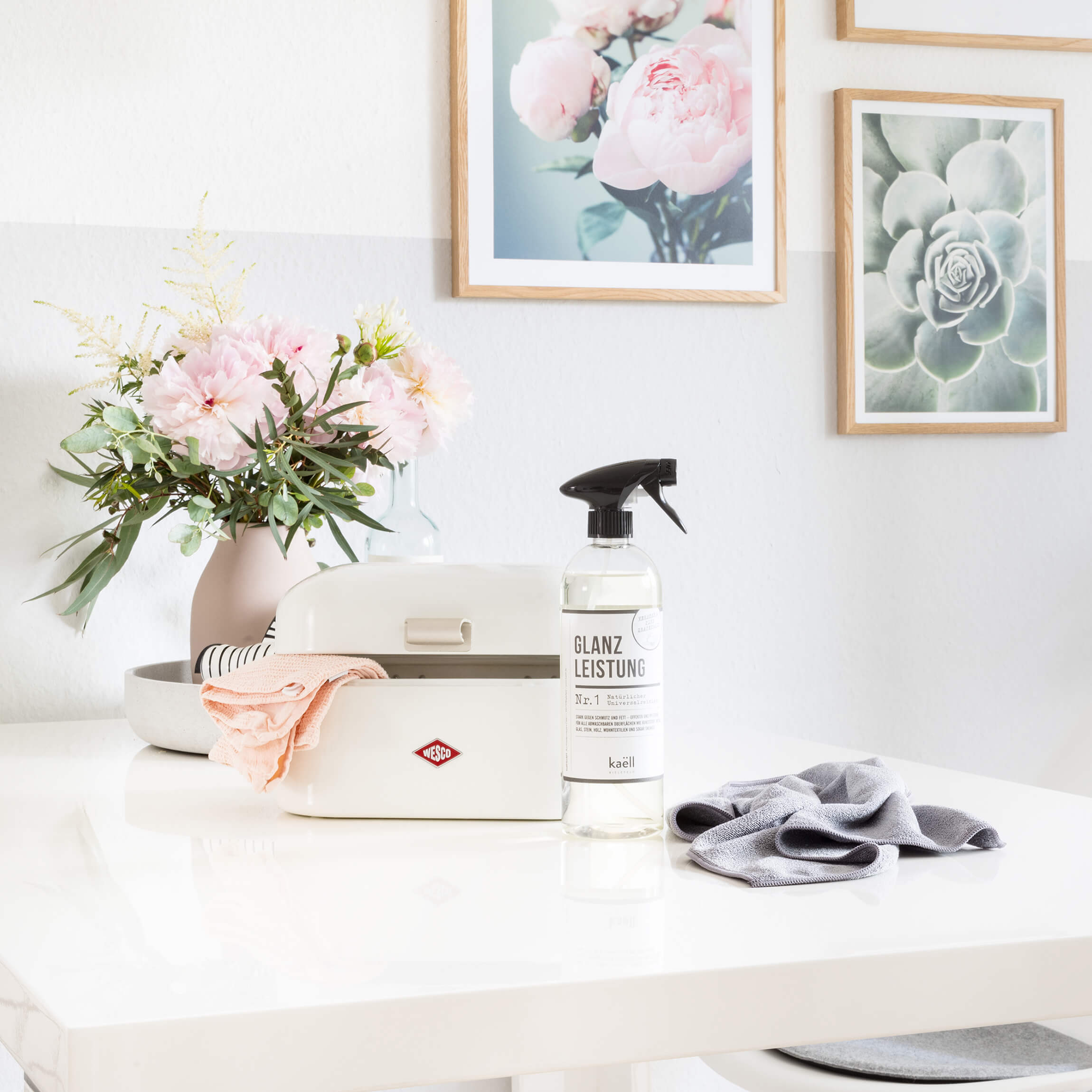 Single grandy used to store cleaning supplies with a vase of flowers and cleaning cloths and spray bottle.
