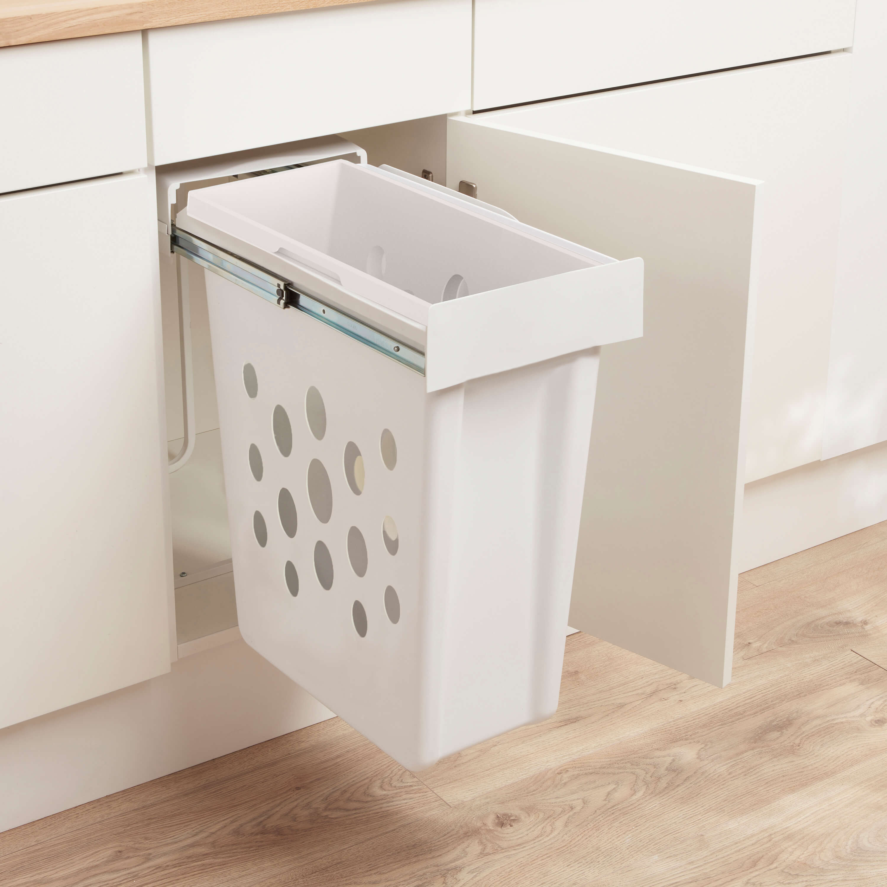Wesco Laundry boy, a White laundry basket with perforated design on runners within a kitchen cabinet