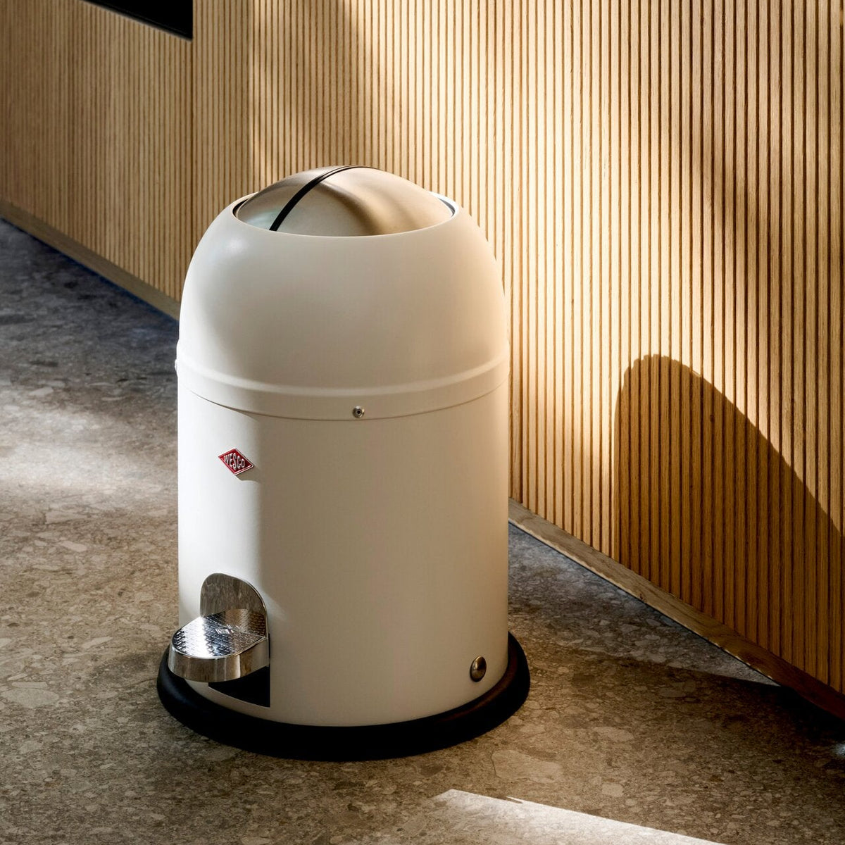 Wesco Mini master 6L pedal in ext to a wooden cabinet placed on a dark stone floor