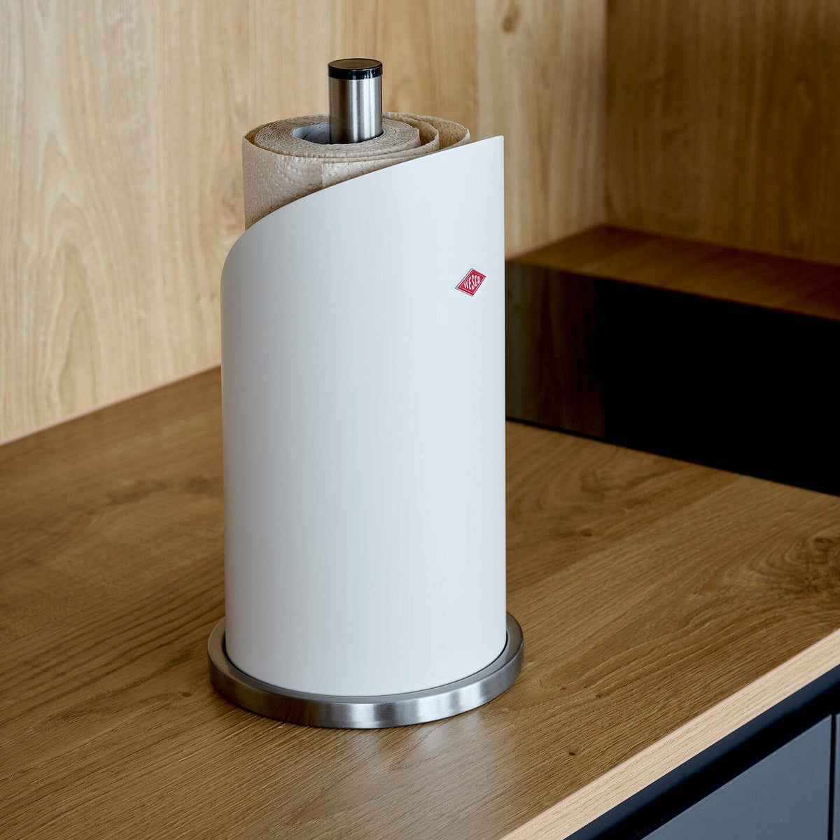 Wesco Matt White Paper Roll Holder on a wooden worktop and splash back with dark blue cabinets 