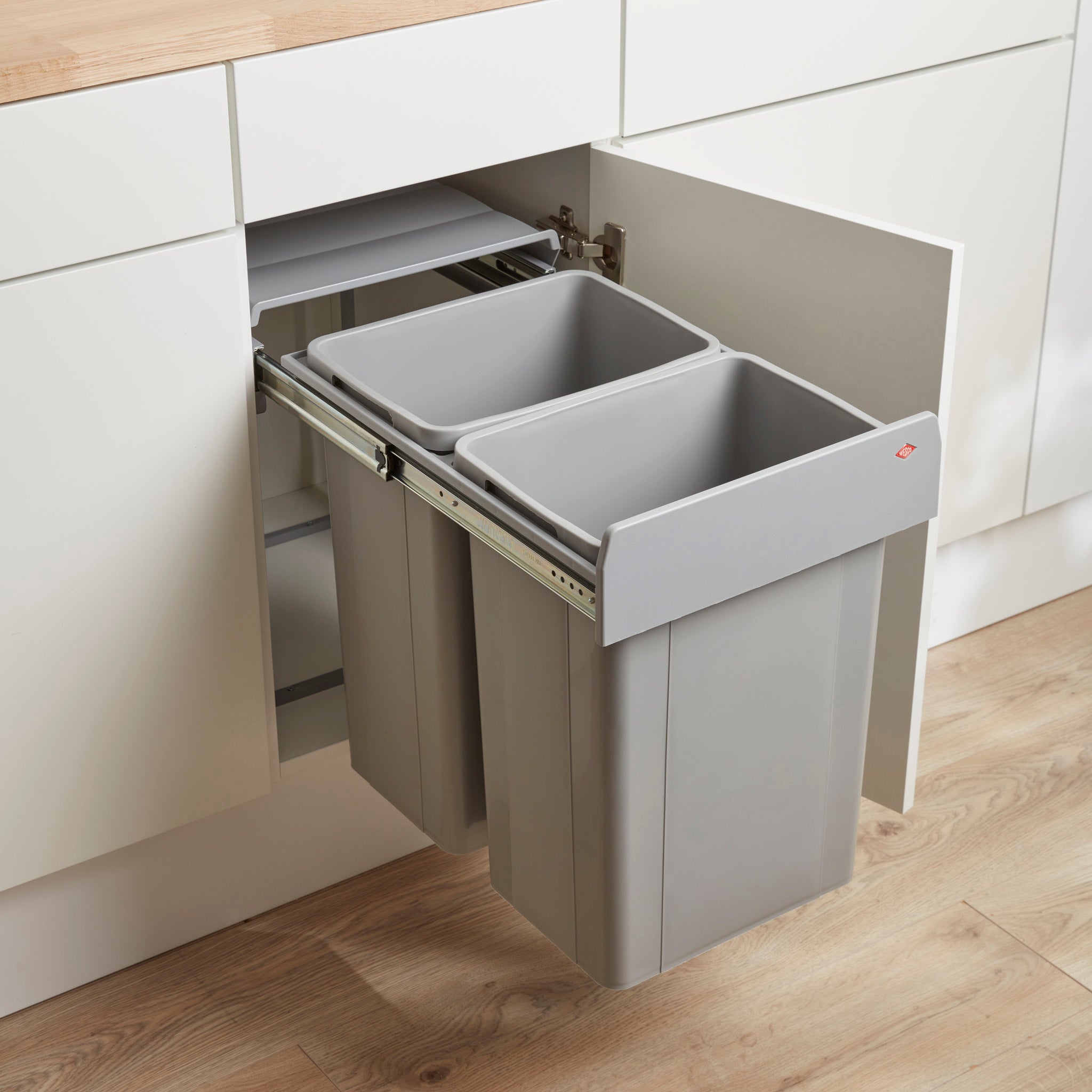 A grey built-in recycling bin system pull-out fitted into a kitchen cabinet, with two bin compartments visible.